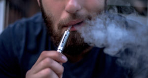 closeup of man vaping as he ponders what employers need to know about e-cigarettes