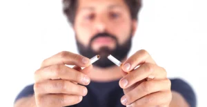 Hispanic man snapping a cigarette to emphasize the importance of quit smoking in Spanish programs.